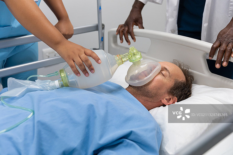 各色男女医生给躺在床上的病人戴上氧气面罩图片素材