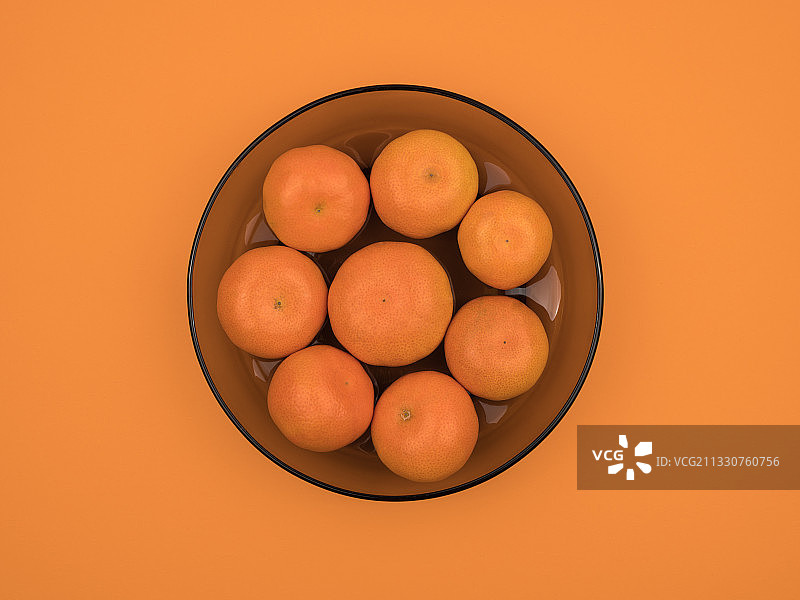 在橙色背景上方的碗里的橙子图片素材