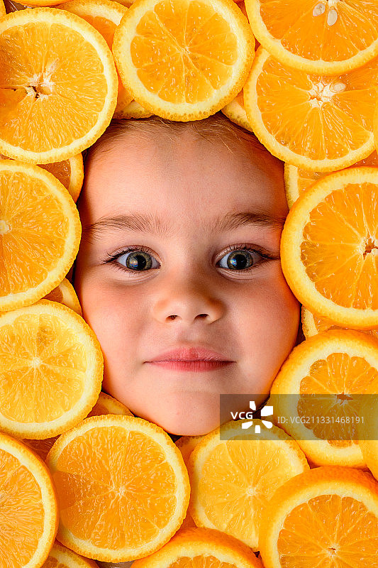 一个美丽的小女孩的脸被橙子片包围着图片素材