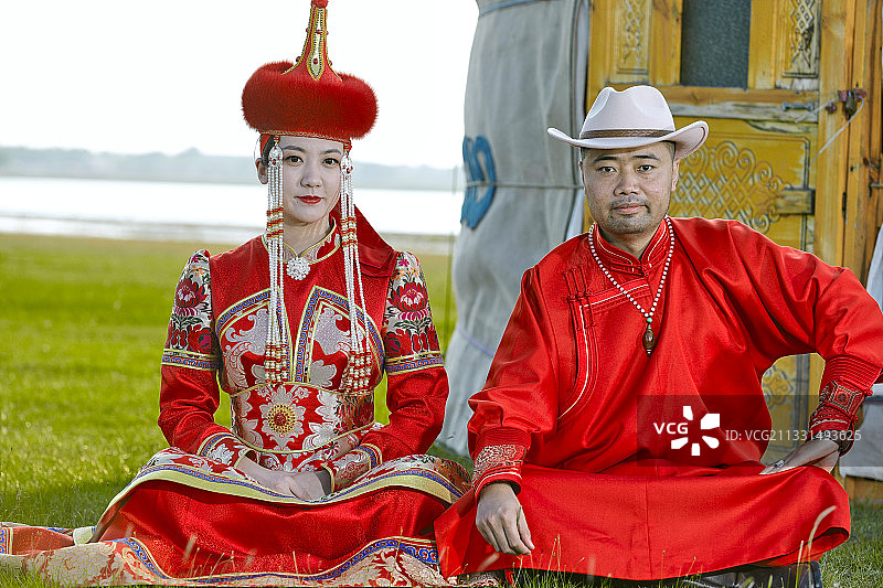 草原上蒙古包前穿蒙古族传统服饰的年轻夫妻图片素材