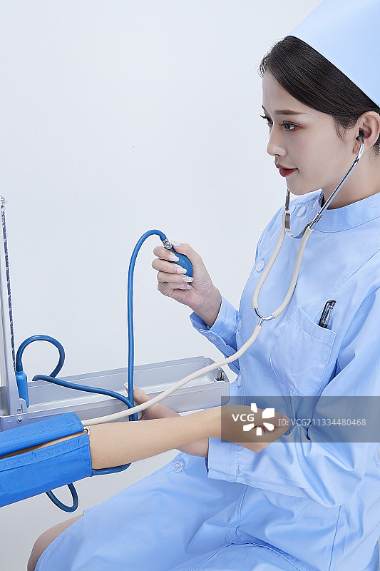 手拿血压测量仪为患者诊治量血压的女性护士图片素材