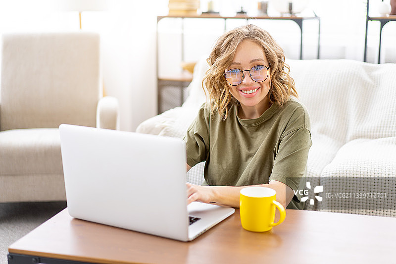 微笑的女人在家里使用笔记本电脑的肖像图片素材
