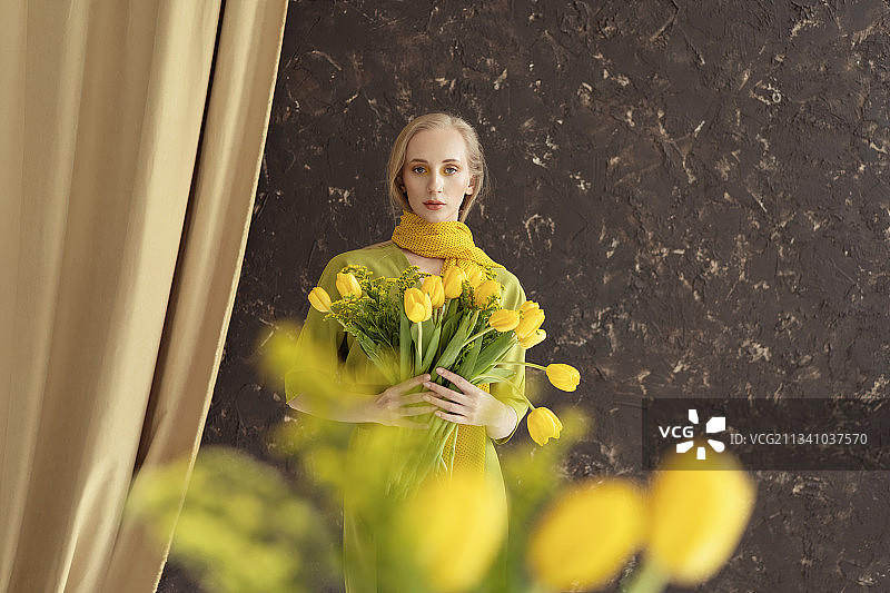 俄罗斯，一名年轻女子在室内手持黄花图片素材