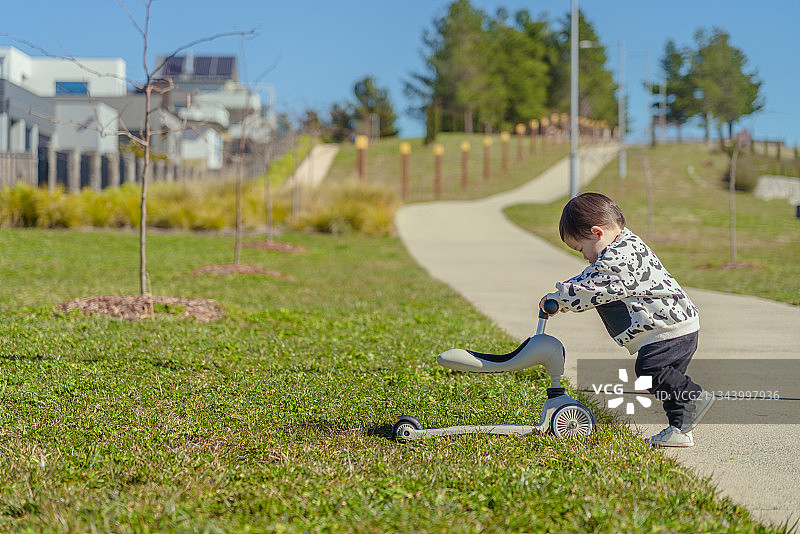 别墅区前山坡草坪上推车回家的小男孩的图片素材