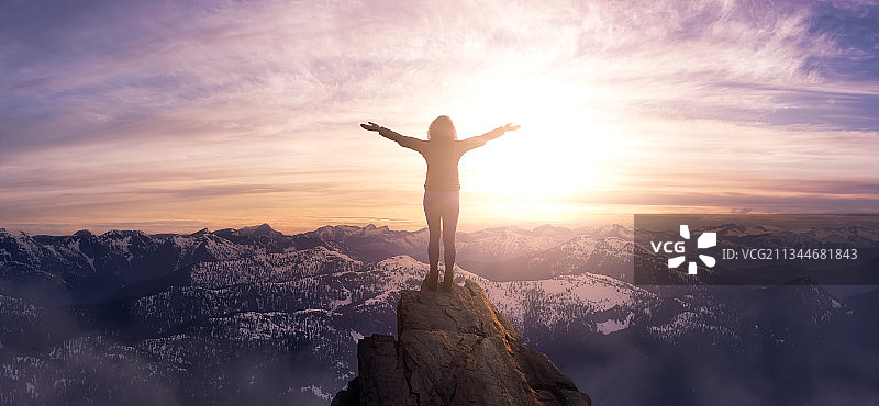 日落时分，女人站在山顶，双臂张开，对着天空图片素材