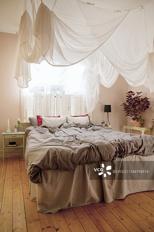 卧室的双人床上方的天篷与木地板图片素材