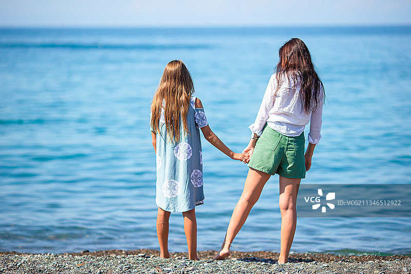 美丽的母亲和女儿在海滩上享受暑假图片素材