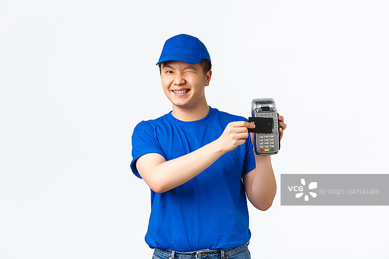 一名微笑的年轻男子手持相机，站在白色背景下图片素材