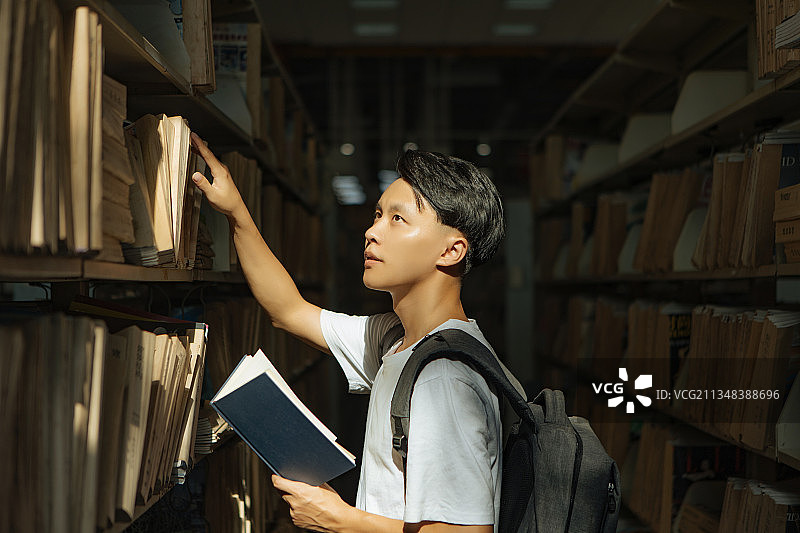 亚洲青年男性在图书馆档案室里的阅读图片素材