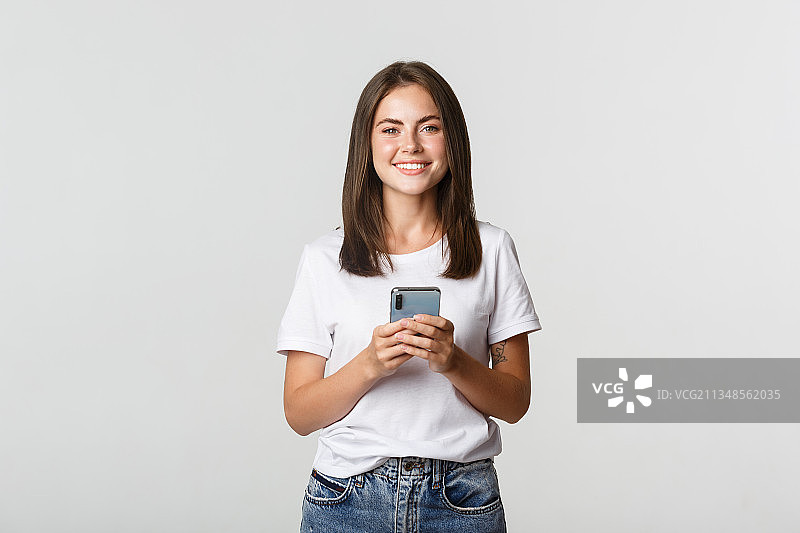 微笑的年轻女子肖像使用手机在白色背景图片素材