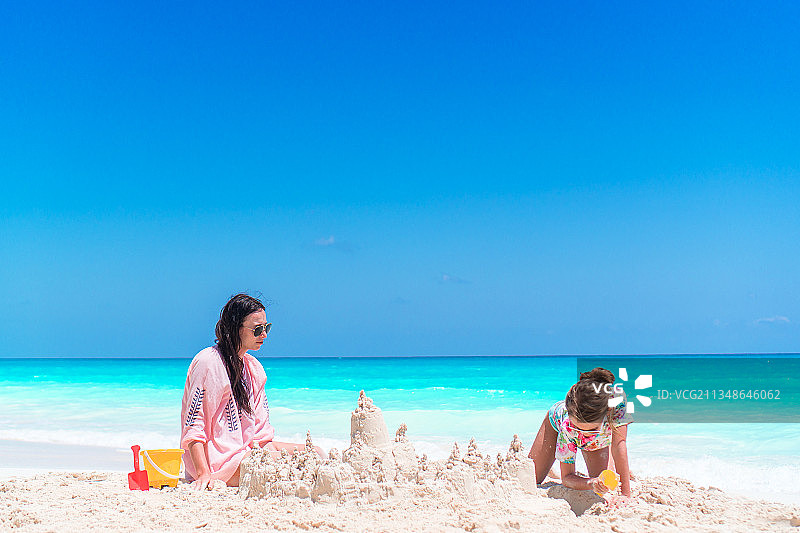 可爱的小女孩和年轻的妈妈在热带海滩上图片素材