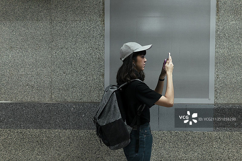 侧面的亚洲泰国背包女旅行者戴着帽子走在地铁地下的白板前拷贝空间。图片素材