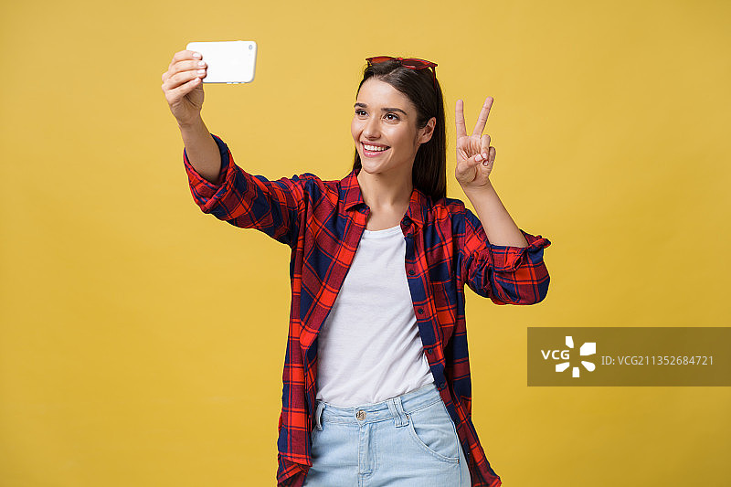 年轻女子手持信用卡，面带微笑，站在黄色背景下图片素材