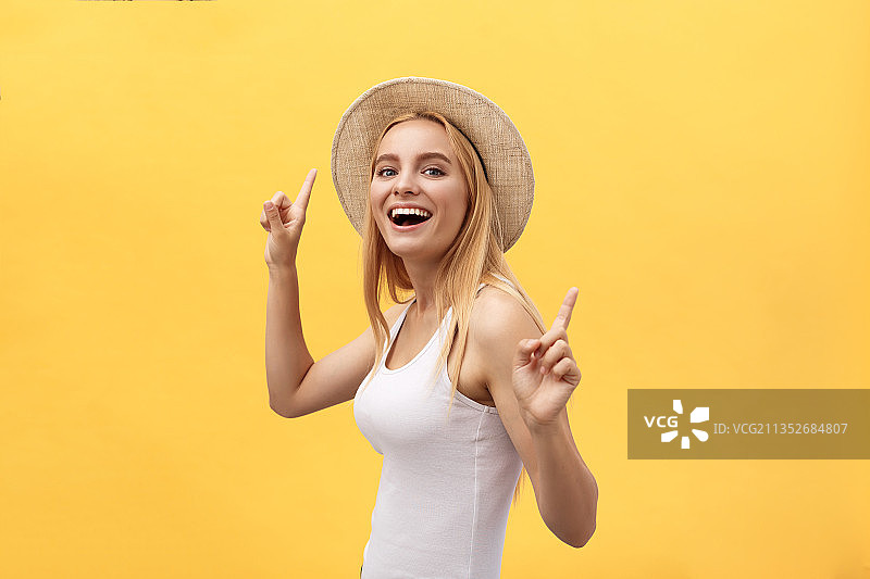 微笑的年轻女子肖像，站在黄色的背景下做手势图片素材