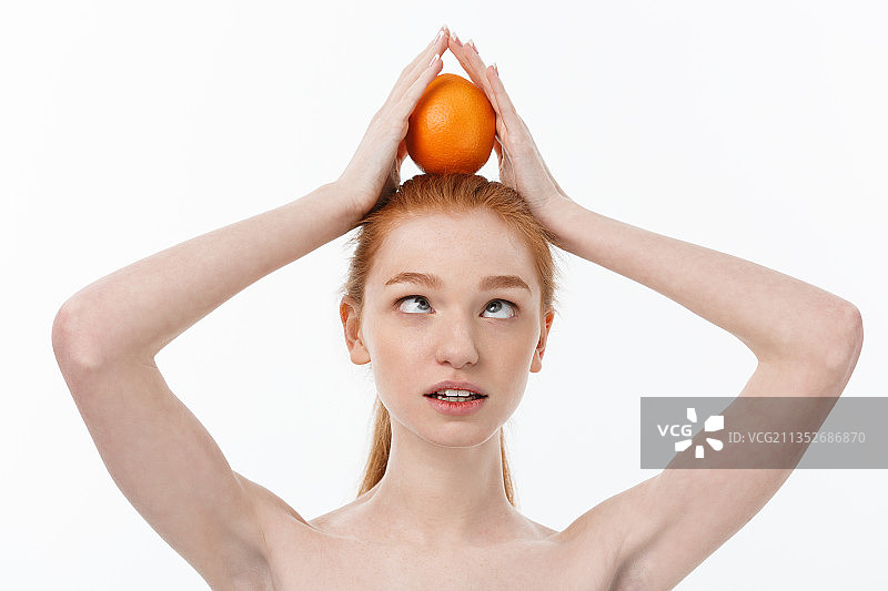 年轻女子拿着橙色的水果在白色的背景下图片素材