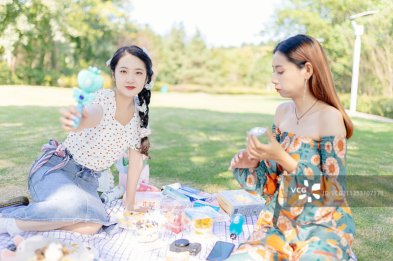 两个亚洲青年美女闺蜜在户外野餐垫上野餐图片素材