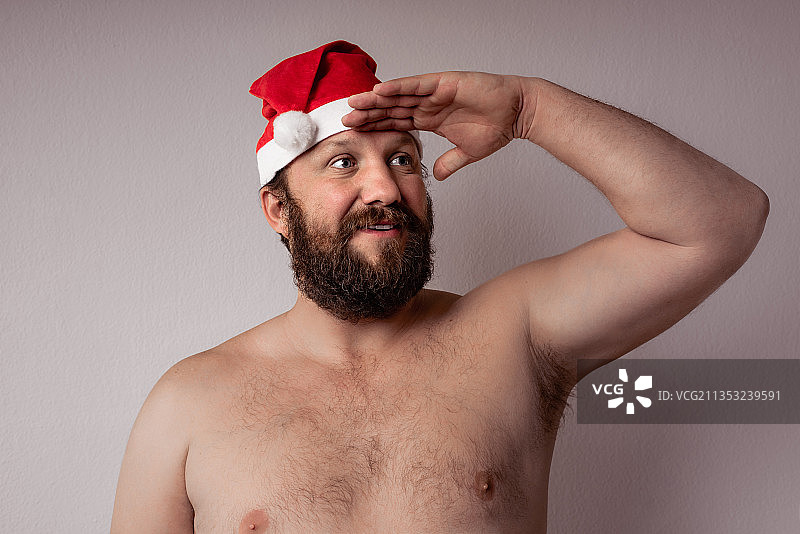 有胡子的男人的肖像戴着圣诞老人的帽子在灰色的背景图片素材