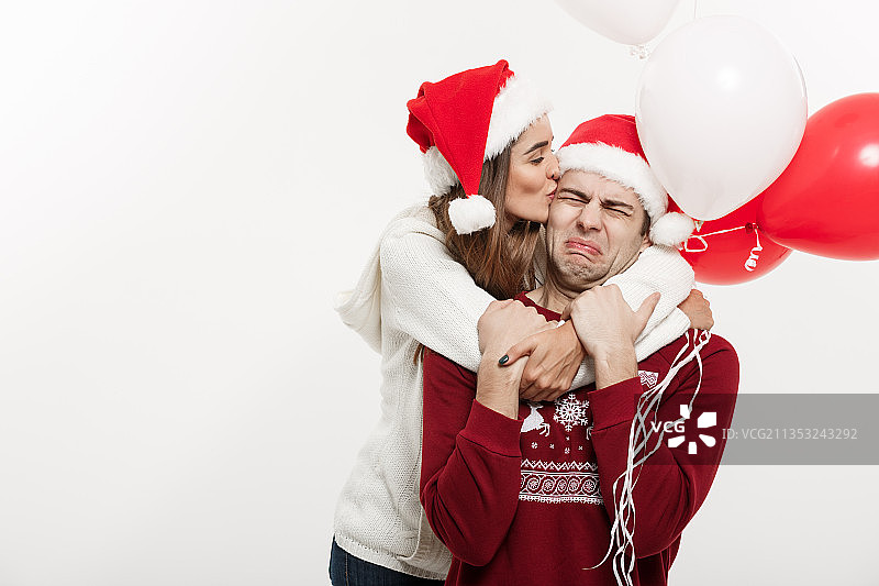 一对夫妇戴着圣诞老人的帽子站在白色背景下图片素材