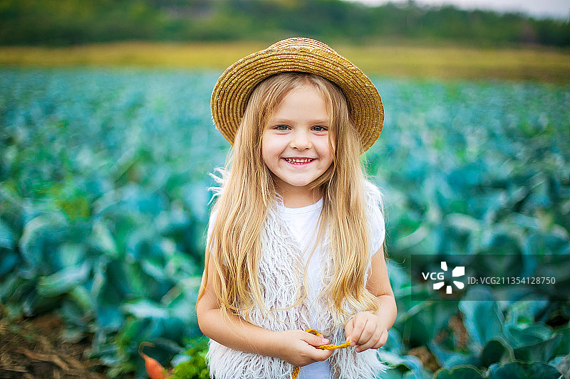 卷心菜地里戴着草帽的快乐女孩图片素材