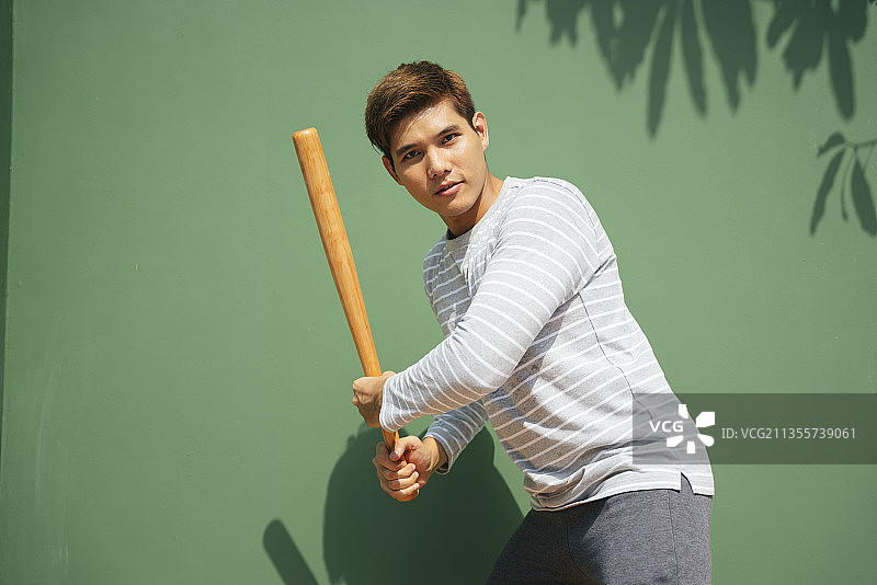 英俊的亚洲人拿着棒球棒。准备击球姿势。棒球运动员拿着棒球棒。图片素材