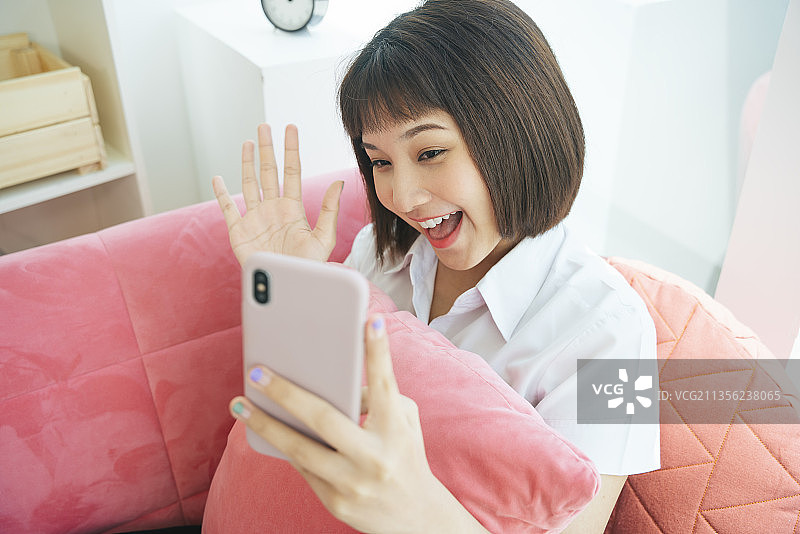 泰国大学女学生呆在家里用智能手机和人们在网上聊天。生活。冒着蒸汽。社交媒体。Covid-19暴发。图片素材