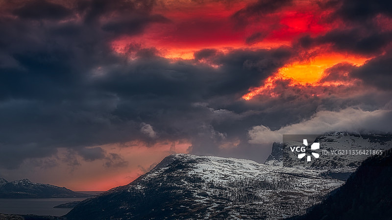 日落时白雪皑皑的山峦在戏剧性的天空衬托下的风景图片素材