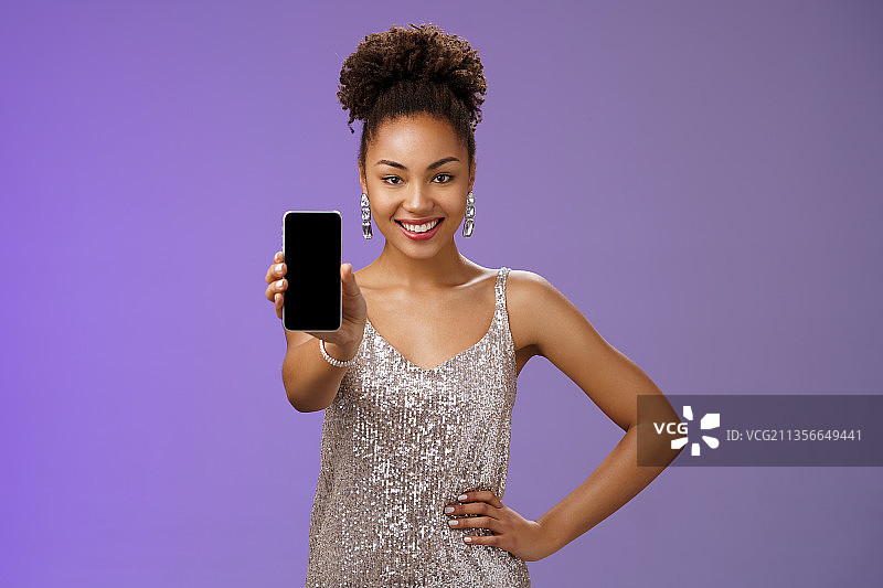 在紫色背景下使用手机的微笑女人的肖像图片素材