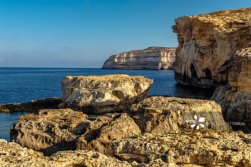 在清澈的蓝天衬托下，海中岩石的风景图片素材