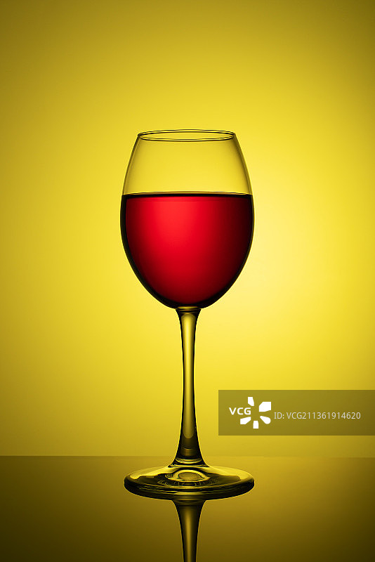 一杯以黄色为背景的红酒图片素材