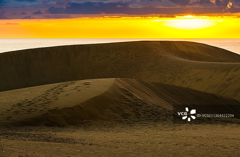 沙漠中的沙丘，日落时天空映衬下的沙漠风景图片素材