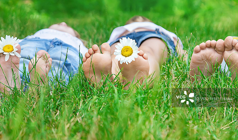 孩子的脚与绿色草地上的甘菊选择性聚焦图片素材