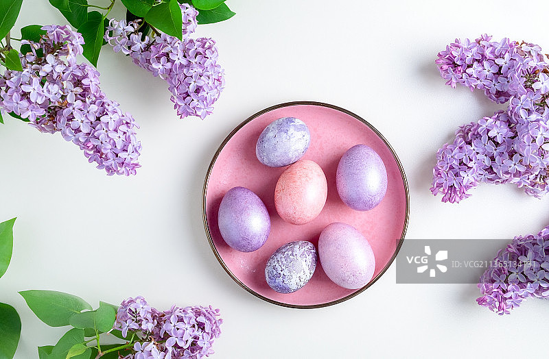 复活节彩蛋放在一个镶有丁香花枝的盘子上图片素材