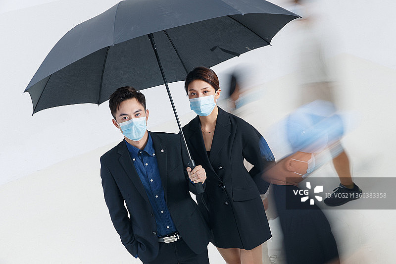 拿着雨伞的商务男女戴着口罩站在人群中图片素材