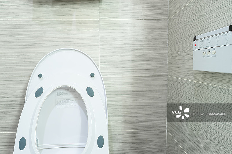 中国家庭室内装修设计，厕所里的智能水洗马桶和悬挂在墙壁上的操作按键面板图片素材