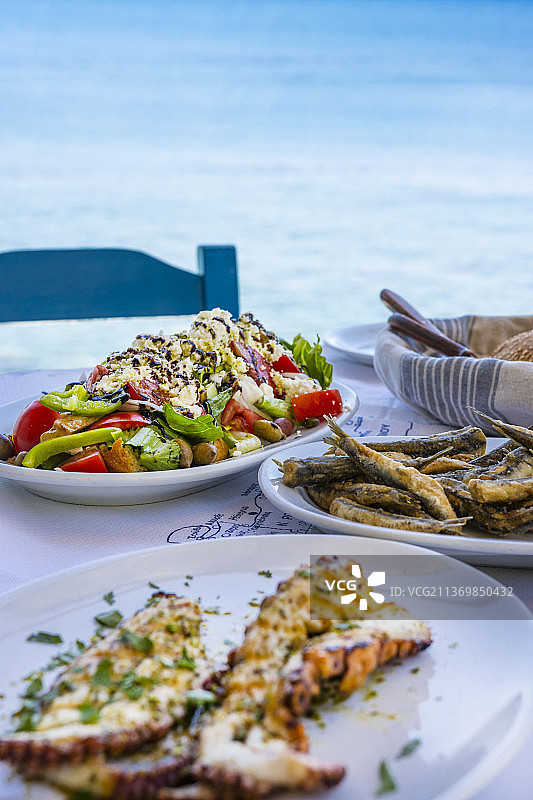 海边的餐桌上有希腊沙拉、章鱼和炸沙丁鱼图片素材