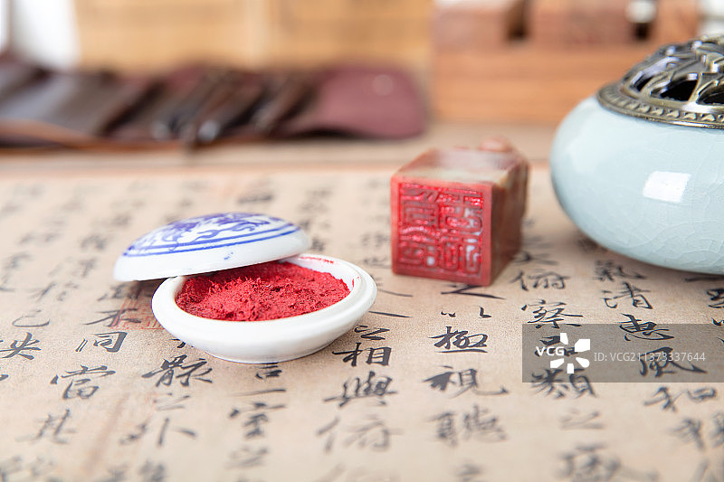 铺开的书法作品和一盒印泥及中国传统篆刻印章图片素材