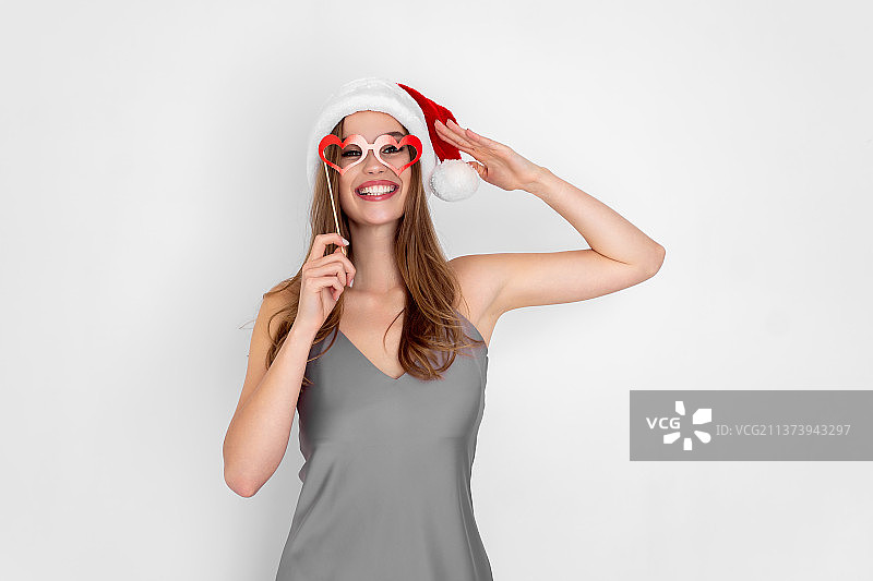 滑稽的女孩戴着圣诞老人的帽子，戴着白色背景上的假心眼镜图片素材
