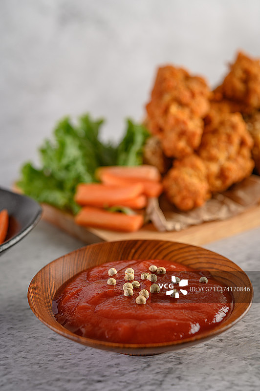 酥脆的炸鸡放在切菜板上，配上番茄酱和胡萝卜图片素材