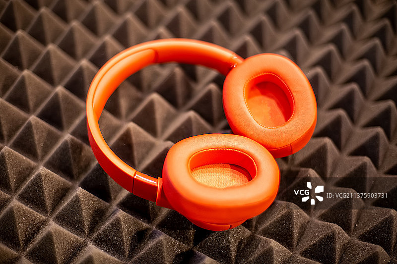 橙色的无线监控耳机放在黑色的泡沫橡胶上图片素材