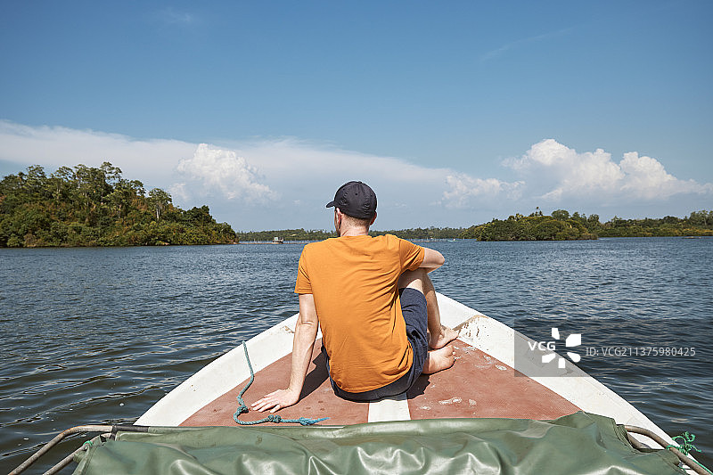 在湖上航行时坐在船头的男子图片素材