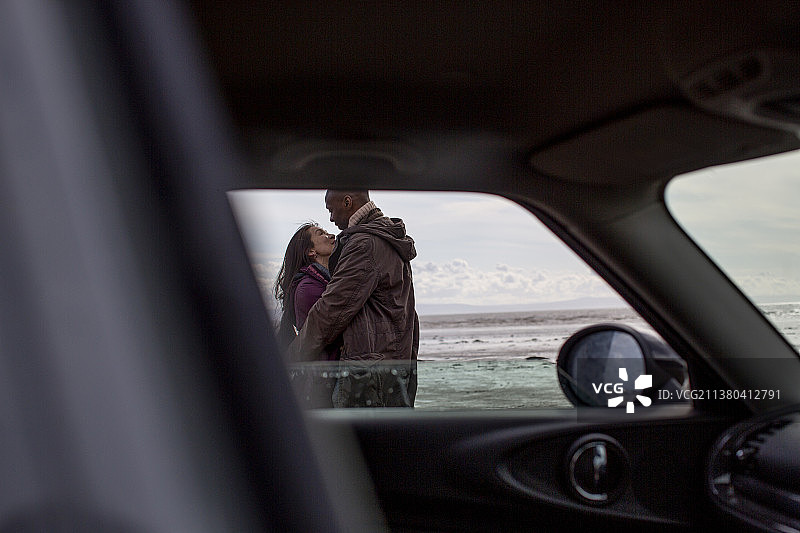 沙滩上，一对深情的情侣在车外拥抱图片素材