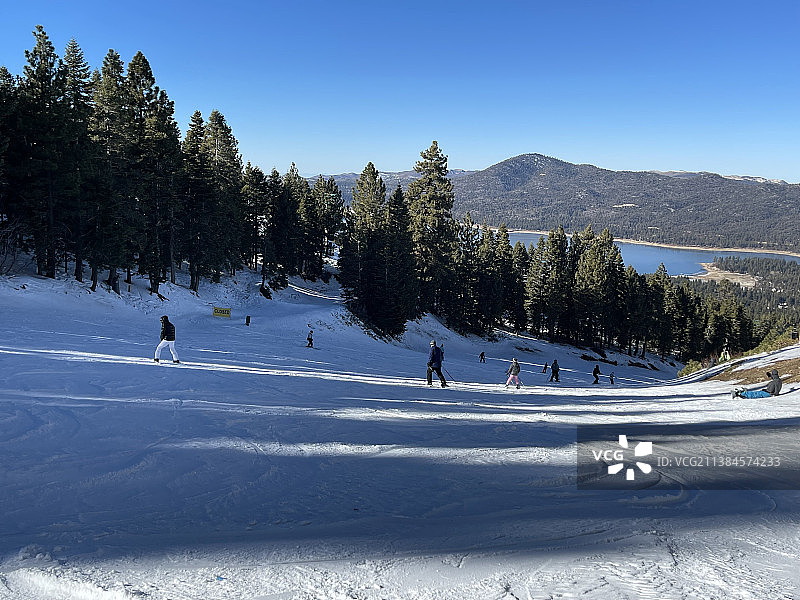 大熊滑雪场，人们在积雪覆盖的景观对晴朗的天空滑雪，圣贝纳迪诺县，加利福尼亚州，美国，美国图片素材