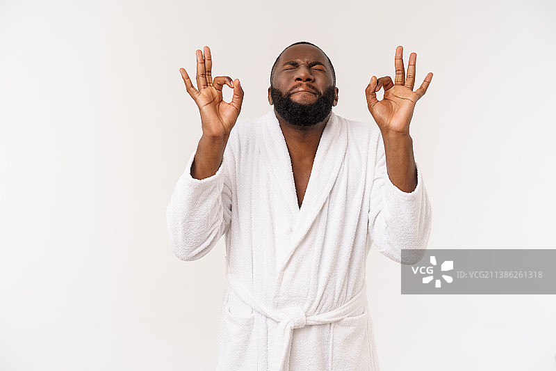年轻的非洲男子穿着浴袍准备进行皮肤护理，露出ok的手指图片素材