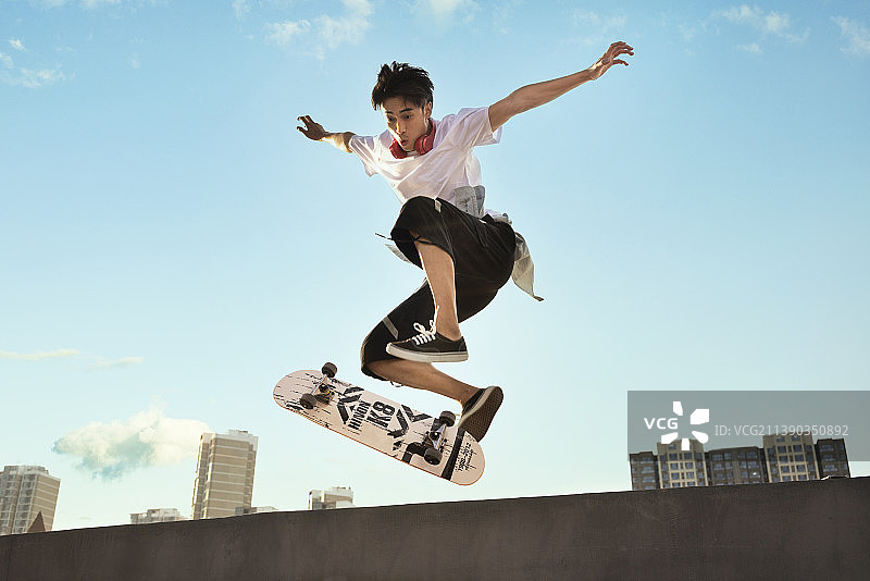 年轻男子滑滑板做极限动作图片素材