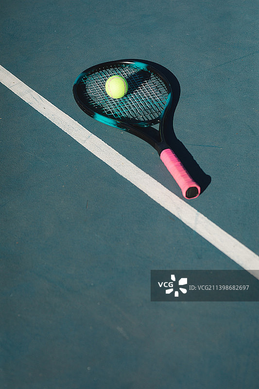 在阳光明媚的日子，网球和球拍的高角度的看法由线在蓝色的球场图片素材