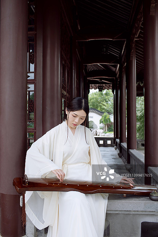 一个古典美女坐在中式长廊里弹古琴图片素材