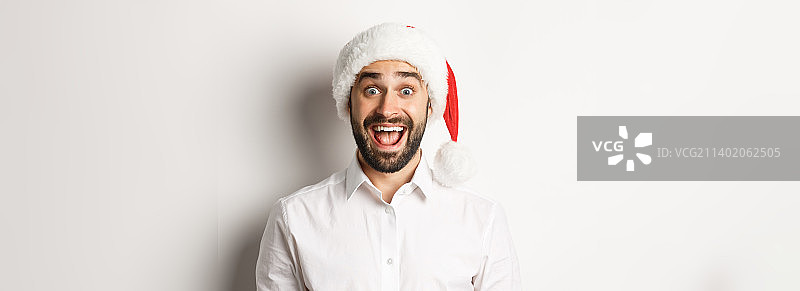 一个戴着圣诞帽的大胡子男人的特写，看起来很惊讶图片素材