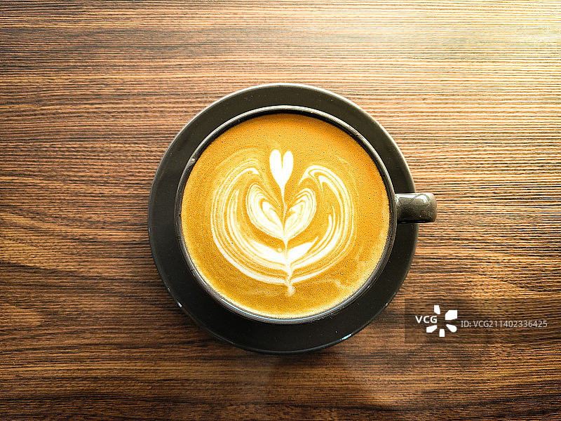 美丽的热咖啡拿铁艺术设计泡沫内黑色杯子与木制背景，马来西亚图片素材