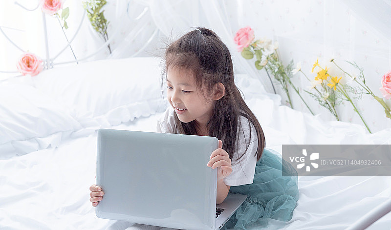 在床上使用笔记本电脑的小女孩图片素材