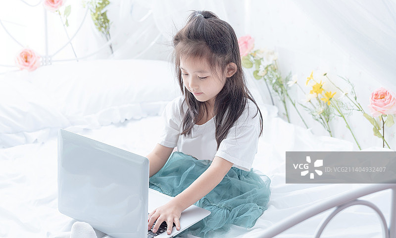 在床上使用笔记本电脑的小女孩图片素材